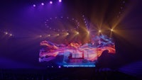 an image of an auditorium with purple lights and a screen