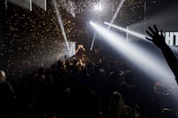 a crowd of people at a nightclub with lights and confetti