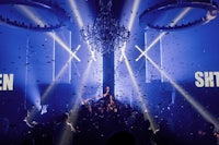 a crowd of people at a nightclub with a chandelier and confetti