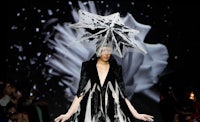 a woman wearing a black and white umbrella on the runway