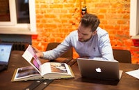 a man sitting at a table with a laptop and an open book